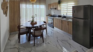 Une cuisine moderne avec coin repas, dotée d’un sol en marbre, de meubles en bois et d’un réfrigérateur en acier inoxydable.