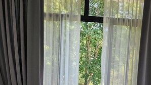 A bedroom with a bed, a chair, and a window with sheer curtains. - Close to several beaches but away from all the hustle and bustle.  (Quebrada Ganado)