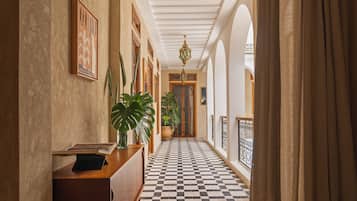 A hallway with checkered flooring, a wooden desk, and a hanging chandelier.