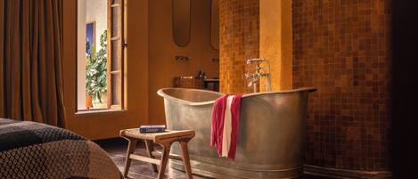 A bathroom with a freestanding bathtub, a wooden stool, and a large mirror.