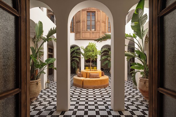 A courtyard with a checkered floor, a central seating area, and large potted plants. - The Mellah Hotel (Marrakech)