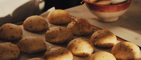 A person seasoning dough balls on a baking tray.