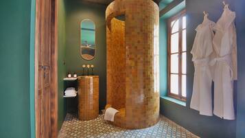 Experience a unique bathroom design with a large mosaic-tiled shower enclosure and a wall-mounted robe rack.
