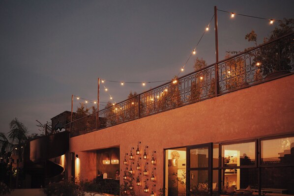 A modern building with a spiral staircase, large windows, and string lights. - The Mellah Hotel (Marrakech)