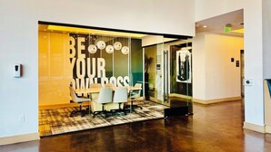 A modern office space with a glass wall displaying motivational text, a conference table, and office chairs. - Clover Street Lofts (Dallas)