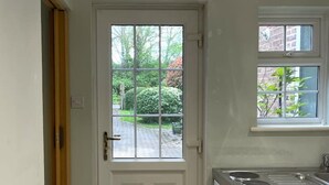 Una cuina compacta amb una estufa blanca, un finestre petit i una porta que dona a l'exterior.