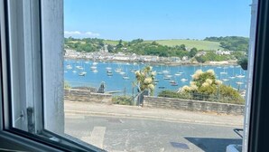 Vista de un puerto con barcos, una carretera y vegetación al fondo.