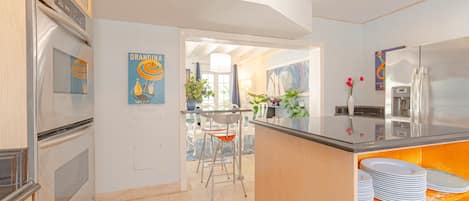 Una cocina moderna con electrodomésticos de acero inoxidable, una isla central con asientos y vista al área de comedor.
