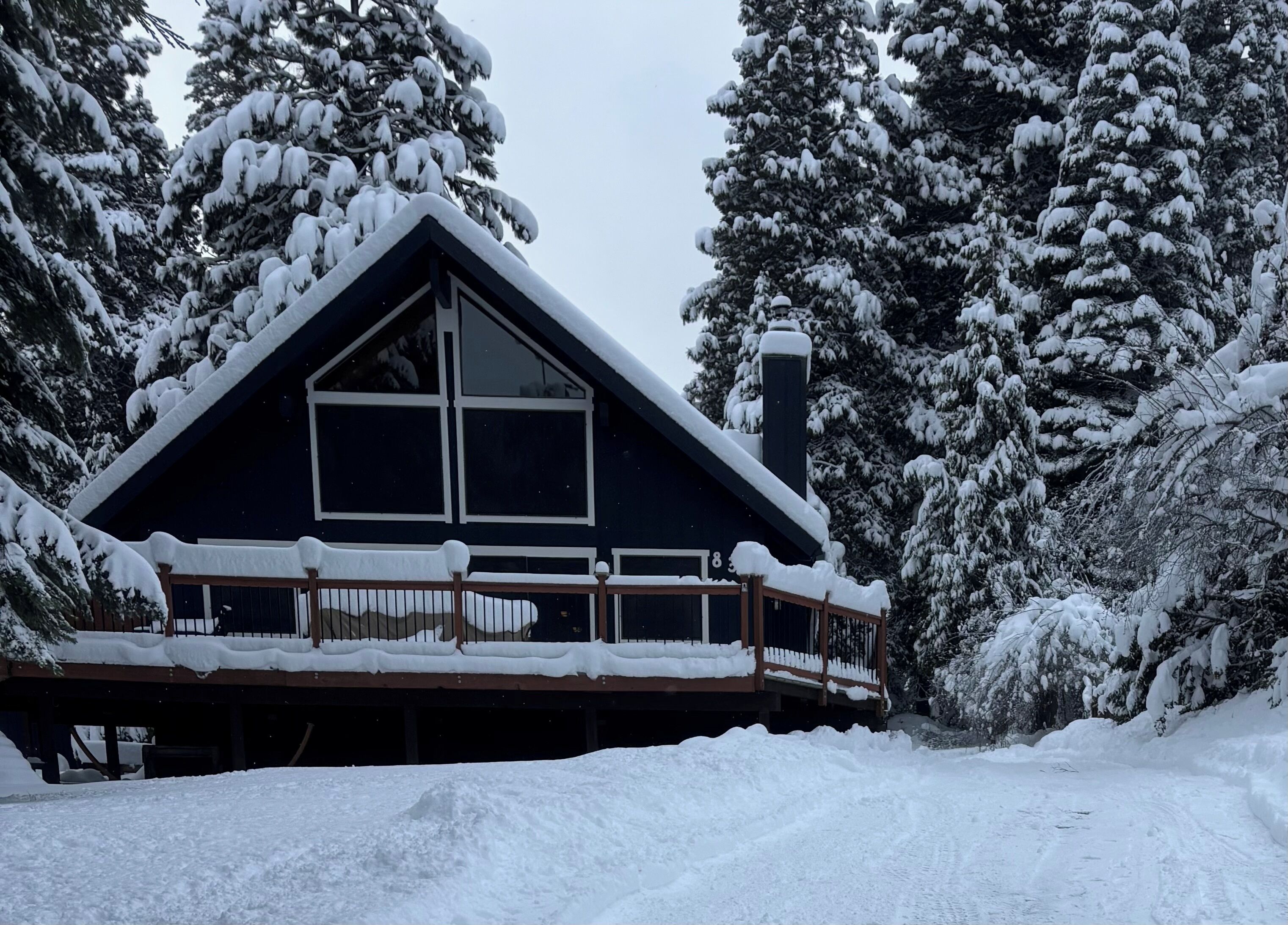 A cabin with a steeply pitched roof, large windows, and a wooden deck.