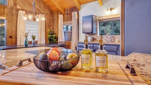 A kitchen with a wooden island, a fruit bowl, and two bottles of oil.