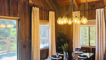 A wooden interior with a dining table set for four, a bench, and a hanging light fixture.