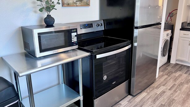 Een kleine keuken met een magnetron, oven en koelkast.