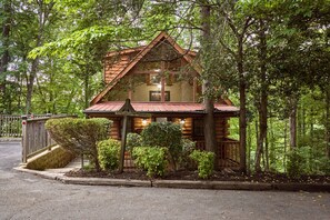 Eine Blockhütte mit einem steilen Dach, umgeben von dichtem Wald.