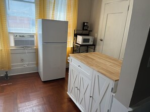 Una cocina con refrigerador, microondas y encimera de madera.