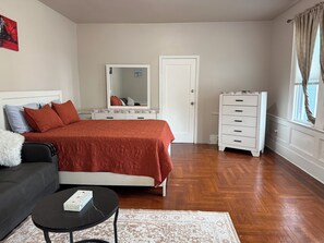 Quarto com cama, penteadeira, espelho, sofá e mesa de centro.