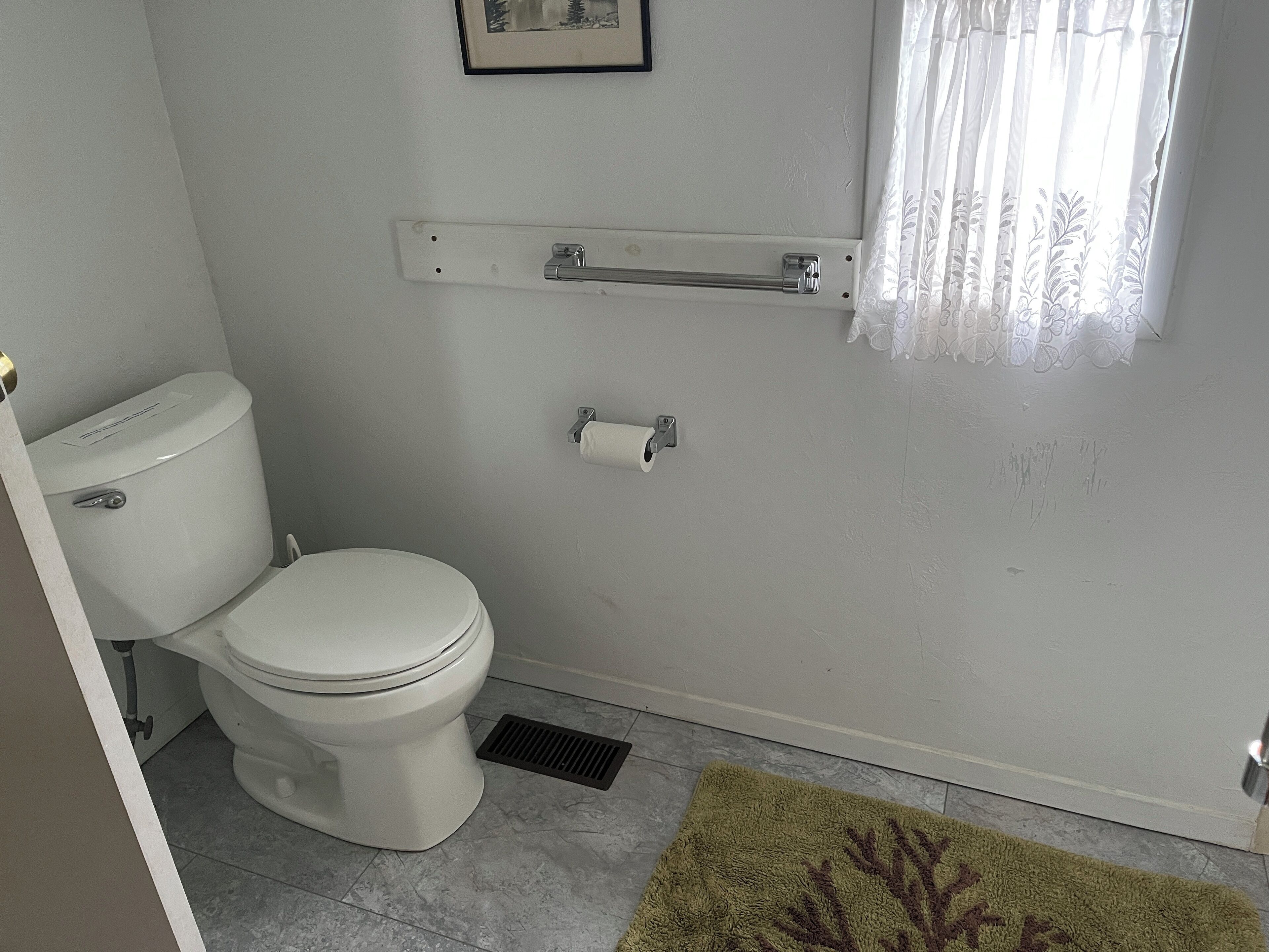 Ein Badezimmer mit Toilette, Handtuchhalter, Toilettenpapierhalter und Duschvorhang.