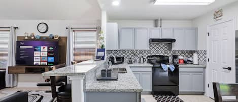 A modern kitchen with a central island, built-in appliances, and a dining area with a TV.