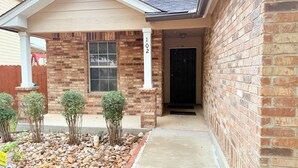 A brick house with a number 102 sign, a front door, and a small garden with rocks and shrubs. - 🌟 Perfect Stay for BMT Graduation • 5 Min to Lackland AFB & SeaWorld (San Antonio)