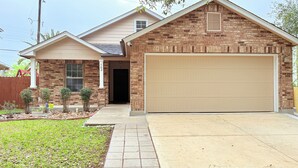 A two-story house with a brick facade, a garage, and a small front yard with plants. - 🌟 Perfect Stay for BMT Graduation • 5 Min to Lackland AFB & SeaWorld (San Antonio)