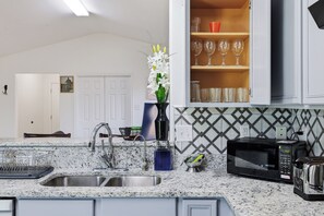 A kitchen with granite countertops, a stainless steel sink, a microwave, and a cabinet with glassware. - 🌟 Perfect Stay for BMT Graduation • 5 Min to Lackland AFB & SeaWorld (San Antonio)