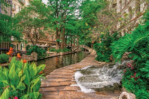 A stone pathway leading to a small waterfall, surrounded by lush greenery and a historic stone bridge. - 🌟 Perfect Stay for BMT Graduation • 5 Min to Lackland AFB & SeaWorld (San Antonio)