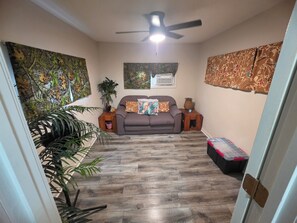 A room with a bed, a ceiling fan, and a window with an air conditioner. - Cumberland Lake House (Nancy)