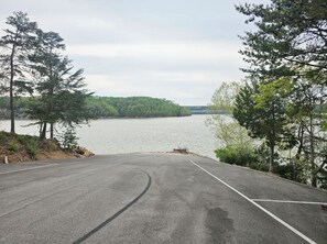 A paved parking area with a view of a lake and forested hills. - Cumberland Lake House (Nancy)