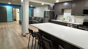 A modern kitchen with a large island, stainless steel appliances, and dark cabinetry.