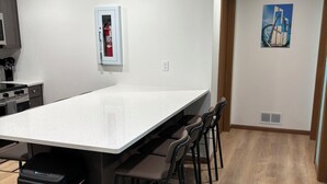 A modern kitchen with a white countertop, black trash bin, and a fire extinguisher on the wall.