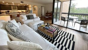 Ein modernes Wohnzimmer mit Sofa, Couchtisch und einem Balkon mit Gartenmöbeln.
