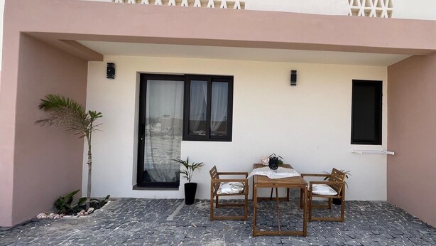 Un bâtiment doté d’un balcon, d’une porte et d’une petite table avec des chaises.