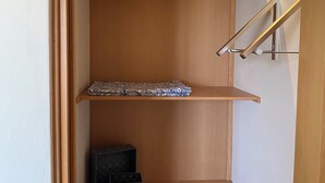 Une étagère en bois à trois niveaux, avec un sac noir sur l’étagère supérieure et une petite boîte noire sur l’étagère inférieure.
