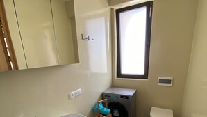 Une petite salle de bain comprenant un lavabo, un miroir, des toilettes et un lave-linge.