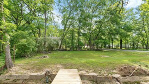 A wooden deck leading into a grassy area with trees and a building in the background. - Modern Charming 3BR/2BA Home. Walking distance to Downtown Benton & Tyndall Park (Benton)
