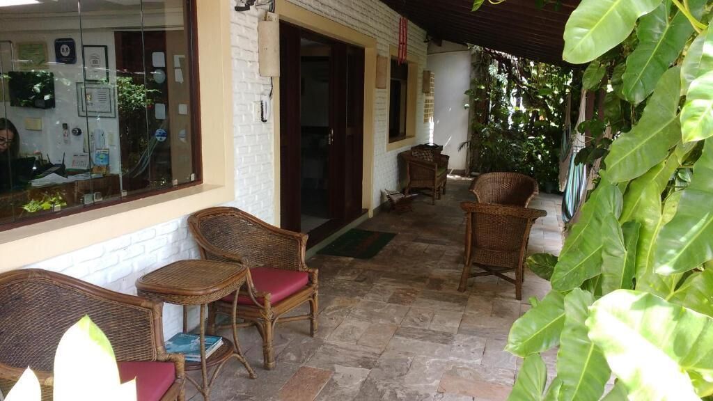A covered outdoor seating area with wicker furniture and a stone floor.