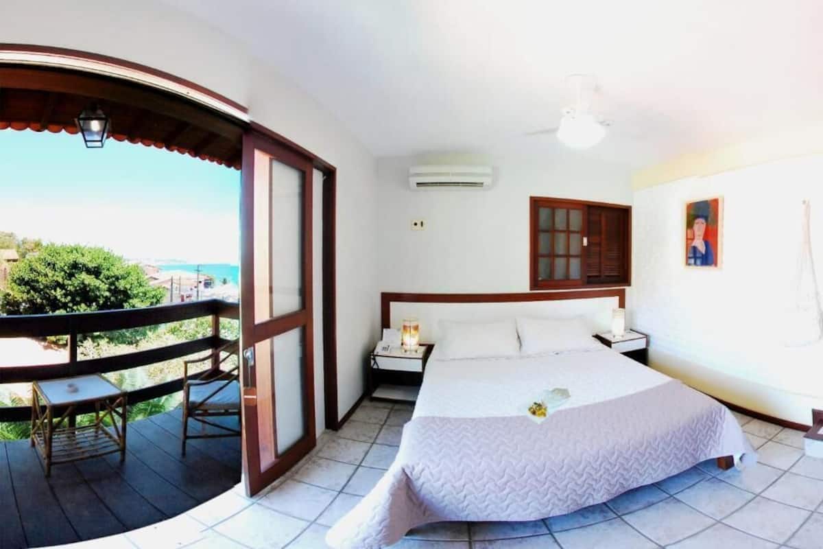 A bedroom with a bed, bedside table, and a view of the outdoors.