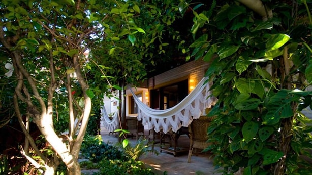 Un jardin avec un hamac, une table en bois et un sentier pavé de pierres.