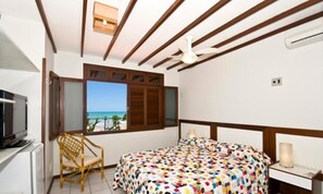 A bedroom with a bed, a chair, a TV, and a window with a view. - POUSADA CASTANHEIRA (Natal)