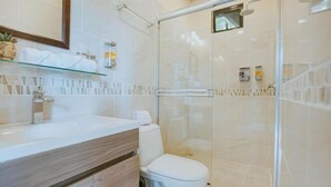 A modern bathroom with a glass shower enclosure, a white sink, and a toilet.