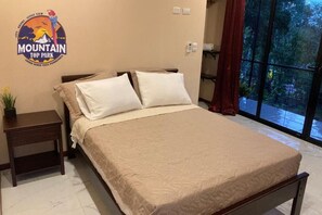 Une chambre à coucher avec un lit, des oreillers, une table de chevet et un logo fixé au mur.