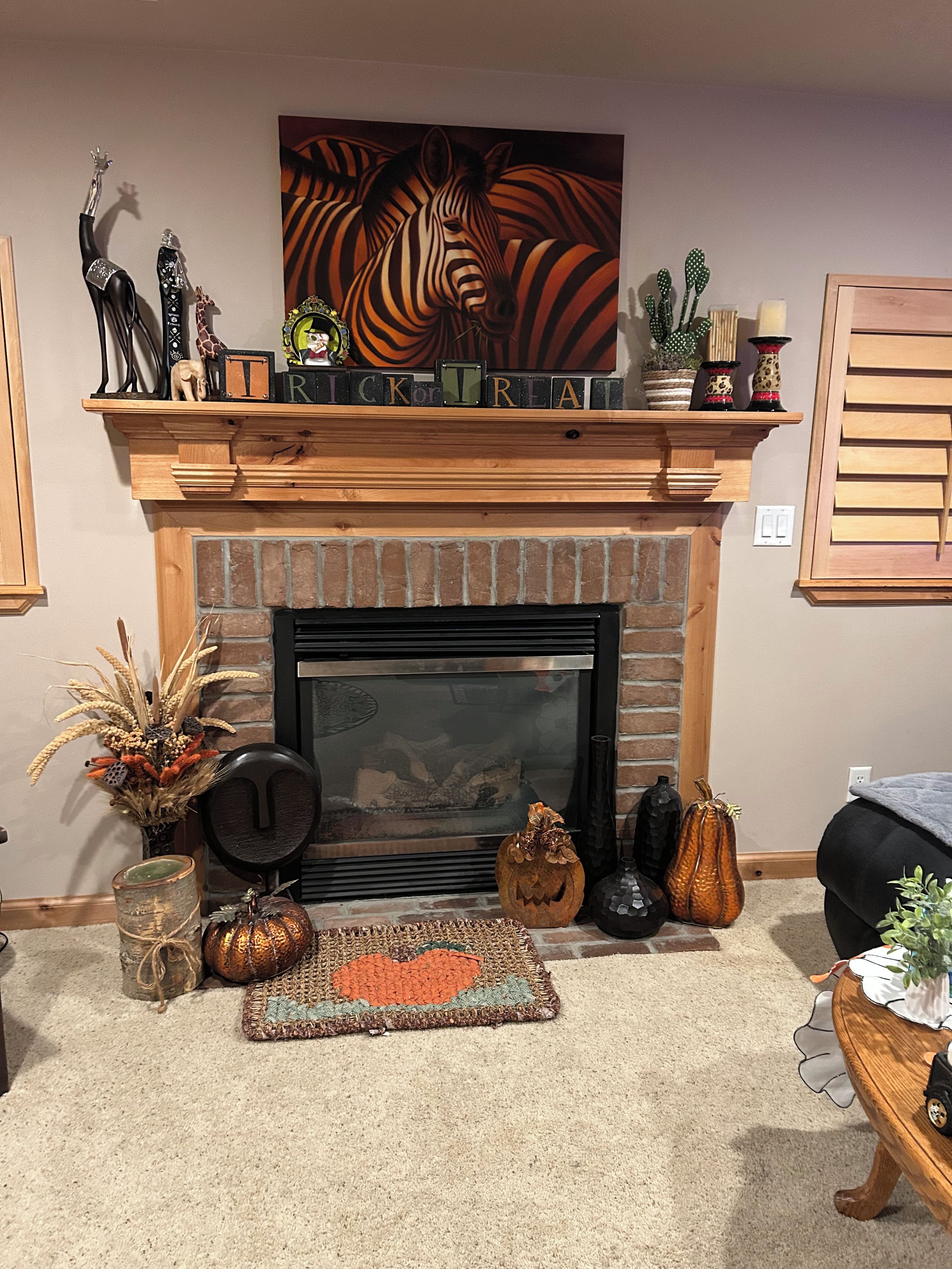 Una chimenea con repisa decorada con varios objetos, incluyendo un cuadro, un letrero y varias esculturas pequeñas.