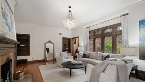 A spacious living room with a fireplace, a large window, and a modern chandelier.
