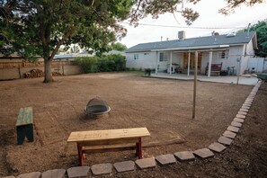 Relax in the serene backyard, surrounded by a tree and a brick border, with a bench and a wheelbarrow nearby.