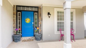 A blue door with a sun design, two potted plants, and a window with blinds. - Cozy Colors Hideaway (Saint Joseph)