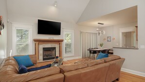 A living room with a large brown leather sofa, a fireplace, and a flat-screen TV mounted on the wall. - Cozy Colors Hideaway (Saint Joseph)