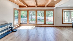 A spacious room with wooden flooring, large windows offering a view of a wooded area, and a built-in bench along one wall. - Spacious Retreat Near Norman Close to OU & Riverwind Casino (Blanchard)