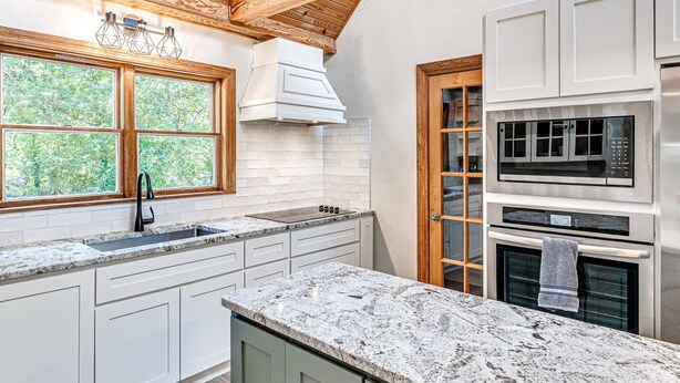 A modern kitchen with white cabinets, granite countertops, and a wooden ceiling. - Spacious Retreat Near Norman Close to OU & Riverwind Casino (Blanchard)