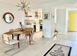 A modern kitchen with white cabinets, a central island, and a hanging light fixture. - Sunrise Villas Condo w/ Pool, Spa & Pickleball Courts in S. Palm Springs (Palm Springs)