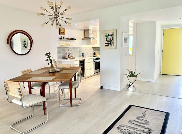 Une cuisine moderne avec des meubles blancs, un îlot central et un luminaire suspendu.