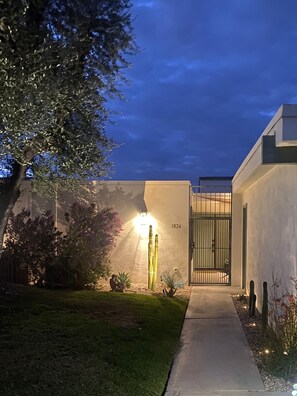 Ein modernes Haus mit gut beleuchtetem Eingang, einem Kaktus im Garten und der Hausnummer 1824 an der Wand.